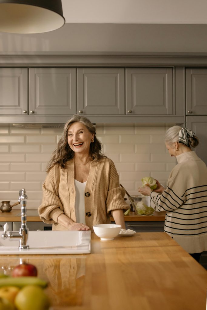 Senior women cooking together in a stylish kitchen, showcasing joyful expressions and food preparation.